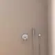Brausearmatur mit Handbrause und Wandhalterung, in Chrom, montiert an einer hellen Wand. Ideal Standard-Design, funktional und klar strukturiert.